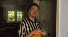 a man in a striped shirt is standing in a kitchen