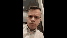 a young man in a white shirt is making a face