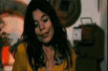 a woman in a yellow shirt is smiling and looking at the camera