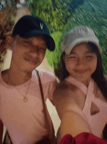 a man and a woman are posing for a picture and the man is wearing a ny hat