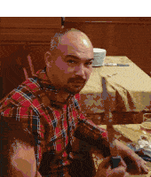 a man in a plaid shirt is sitting at a table