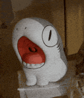 a stuffed animal that looks like a shark with a red mouth