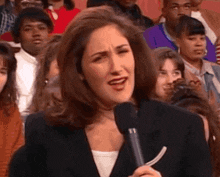 a woman is talking into a microphone in front of a crowd .