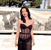 a woman in a black dress is standing in front of a sign that says ' hollywood ' on it