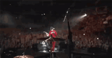 a drummer is playing a drum set on a stage in front of a crowd .