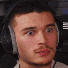 a man wearing headphones is making a surprised face .