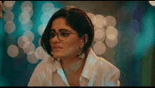 a woman wearing glasses and a white shirt looks at something
