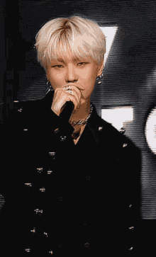 a man with blonde hair is holding a microphone in his hand