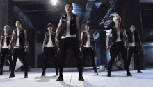 a group of men are dancing on a stage in a dark room