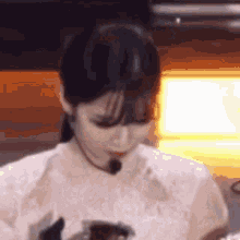 a woman wearing a microphone and a white shirt is looking down .