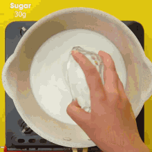 a person pours sugar into a pot of milk