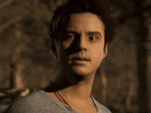 a man with a necklace around his neck looks at the camera