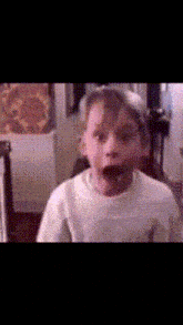 a young boy making a funny face while wearing a white shirt
