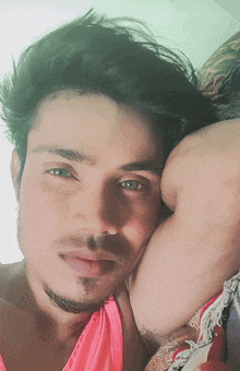a close up of a man 's face with a pink tank top
