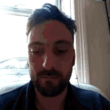 a man with a beard has his eyes closed in front of a window