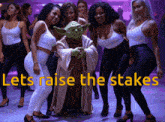 a group of women are standing around a statue of yoda with the words let 's raise the stakes below them