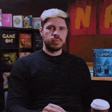 a man sitting in front of a shelf that says game on