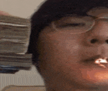 a man wearing glasses is smoking a cigarette while holding a stack of money in his hand