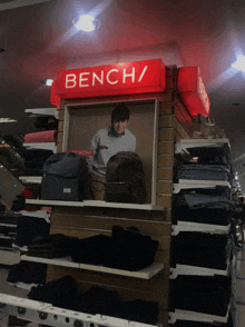 a red bench sign hangs over a display of clothing