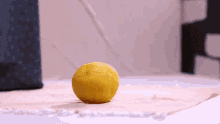 a yellow lemon with holes in it sits on a table cloth
