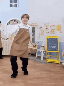 a man wearing an apron is dancing in front of a sign that says open