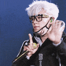a man wearing glasses and a jacket with the letter b on it holds a microphone