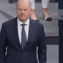 a man in a suit and tie is standing in front of a woman in white pants