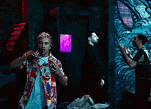 a man in a colorful shirt is singing into a microphone in front of a graffiti wall .