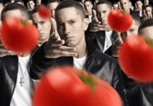 a man in a black jacket is surrounded by many tomatoes .