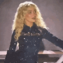 a woman with blonde curly hair is wearing a black jacket with sequins on it .
