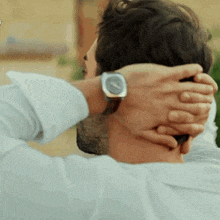 a man wearing a watch is holding his head