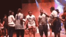 a group of people are standing on a stage dancing .