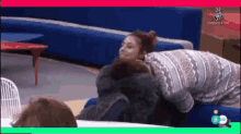 a woman is laying on another woman 's lap in front of a tv screen that says the voice on it