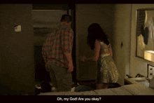 a woman in a gold dress stands next to a man in a plaid shirt in a dark room