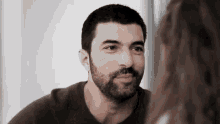 a man with a beard is looking at a woman in the mirror .