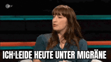 a woman is sitting in front of a microphone on a stage talking about her headache .