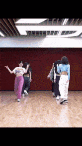 a group of young women are dancing in a dance studio with a red wall behind them