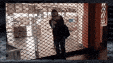 a woman is standing in front of a fence with a sign that says ' x ' on it