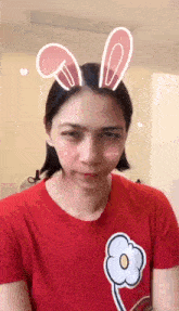 a woman wearing a red shirt and bunny ears on her head