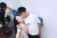 a man kisses a woman on the cheek while wearing a white adidas shirt
