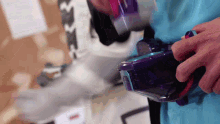 a person in a blue shirt is holding a purple container with the letter b on it