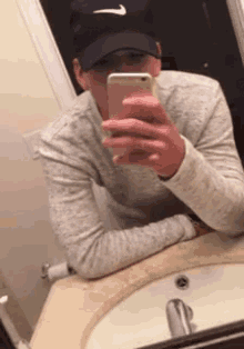 a man wearing a nike hat is taking a selfie with his phone