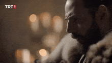 a man with a beard is wearing a fur coat and looking down at something .