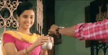 a woman in a pink top is holding a silver container