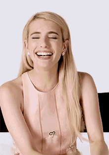 a blonde woman in a pink dress is laughing