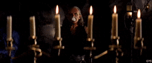 a man standing in front of a row of lit candles .