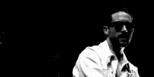 a black and white photo of a man wearing sunglasses and a jacket that says `` lonely ones '' on it .