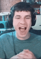 a man wearing headphones and a green shirt is laughing with his mouth open
