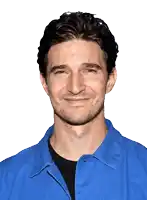 a man wearing a blue shirt and a black shirt smiles