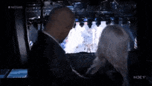 a man and woman are kissing in front of a screen that says nxt .